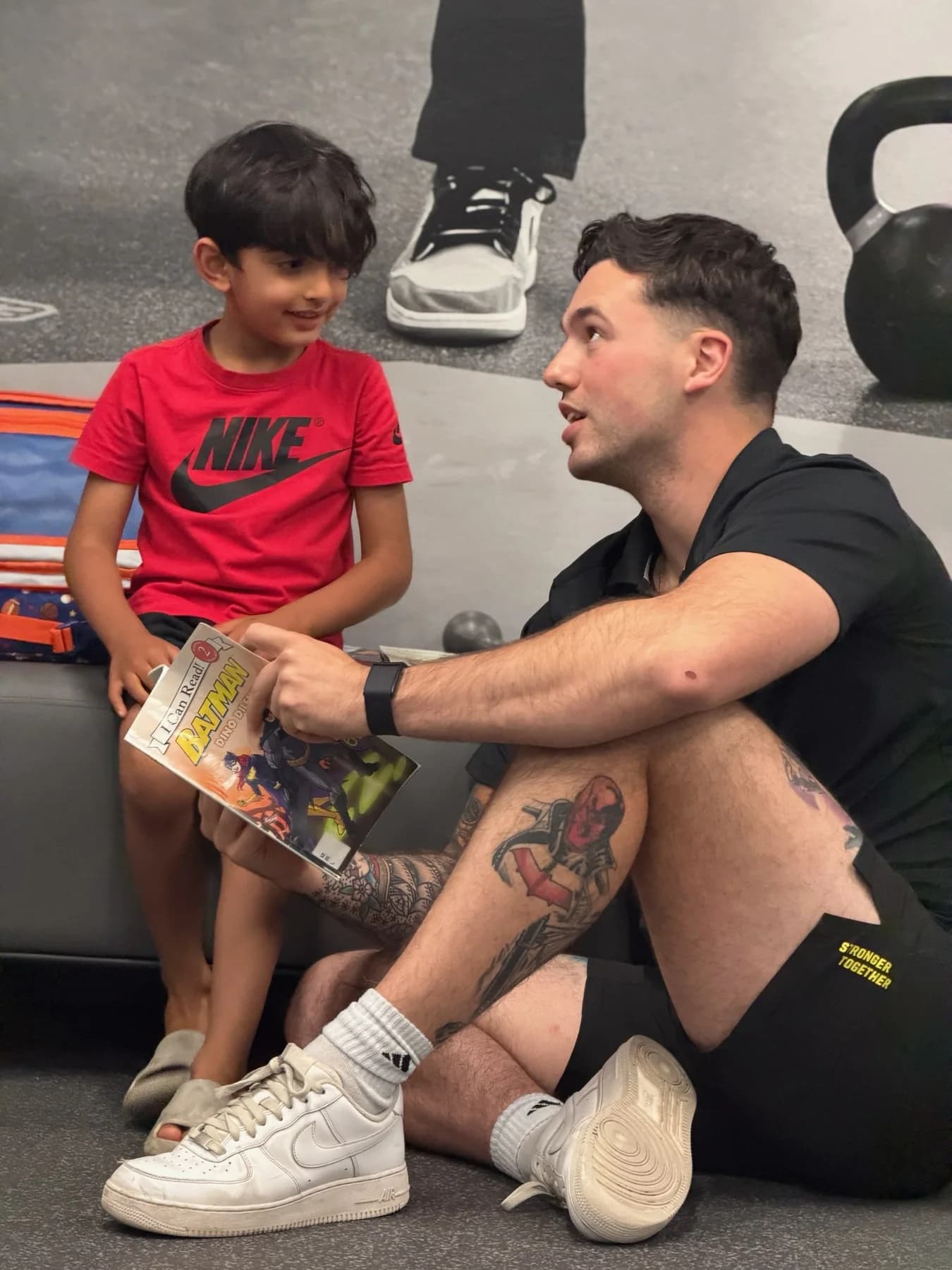 A coach sitting on the studio floor with a young community visitor