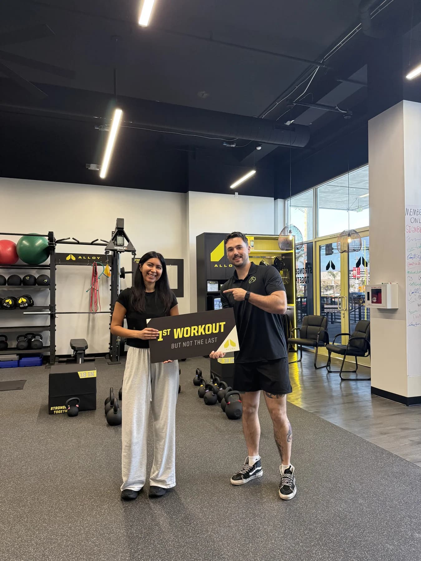 A coach and member posing together after a workout