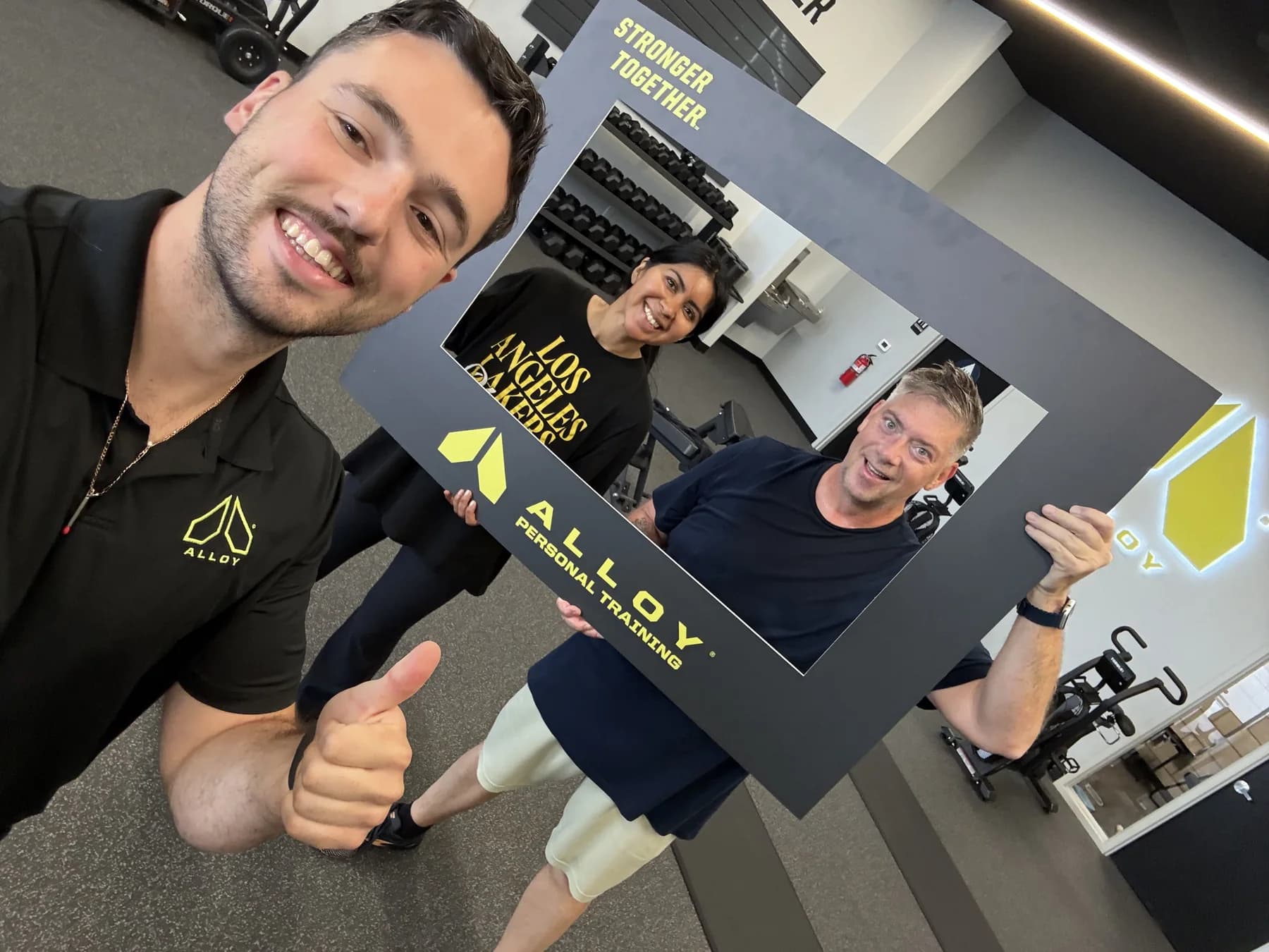 A coach and members taking a playful community-frame selfie