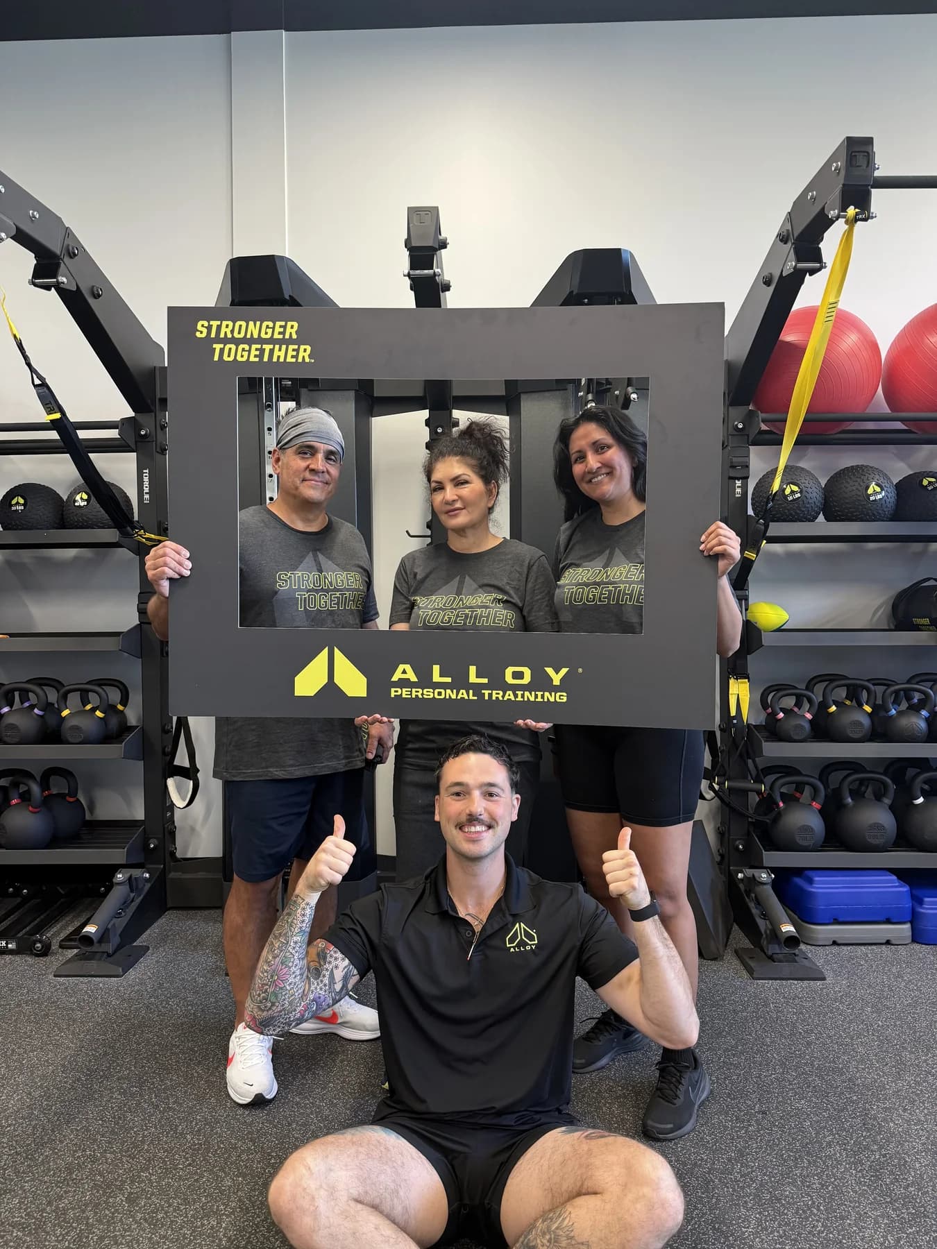 Members and coaches posing with the Alloy Stronger Together frame