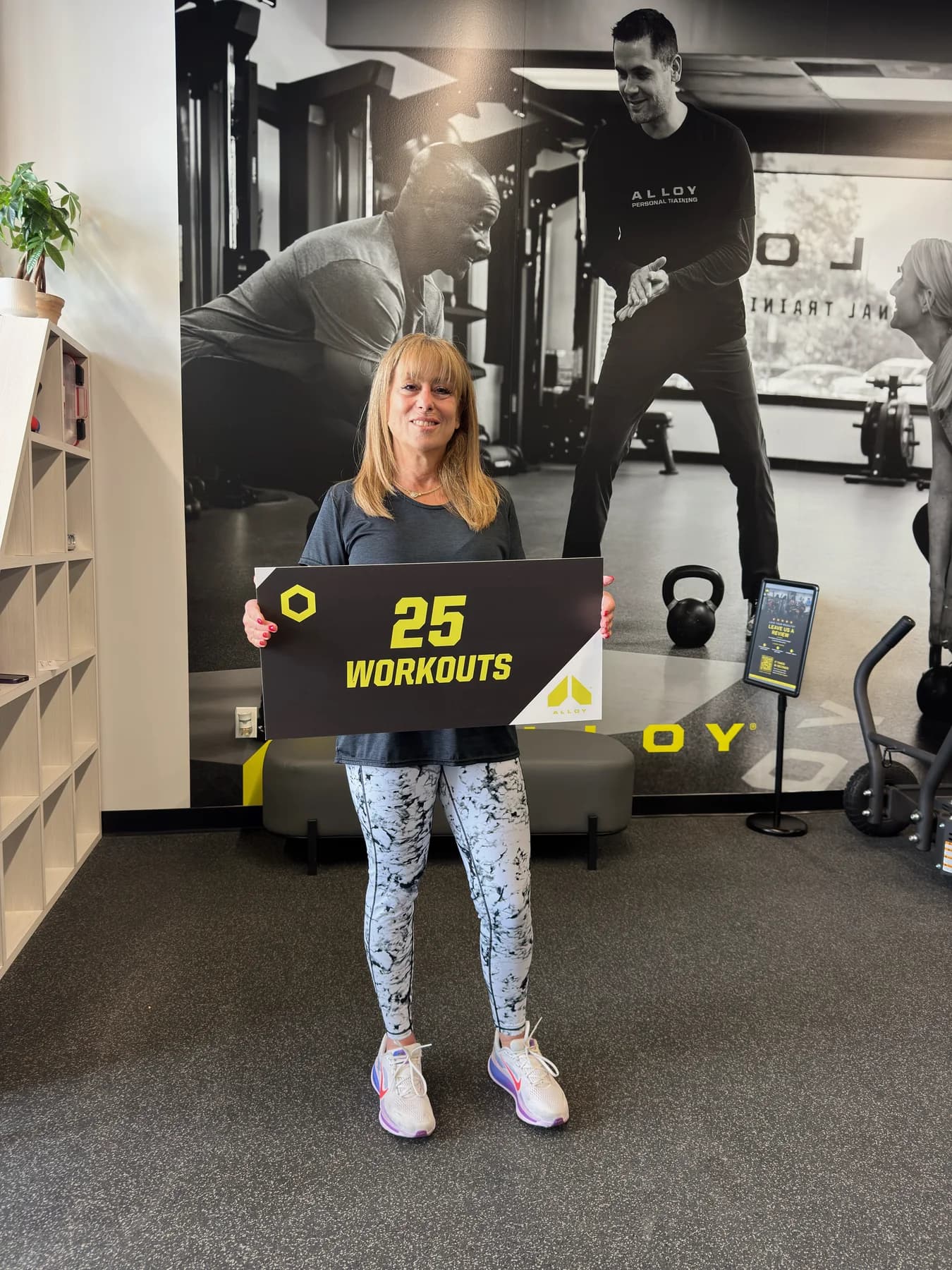 A coach and member celebrating a twenty-five-workout milestone