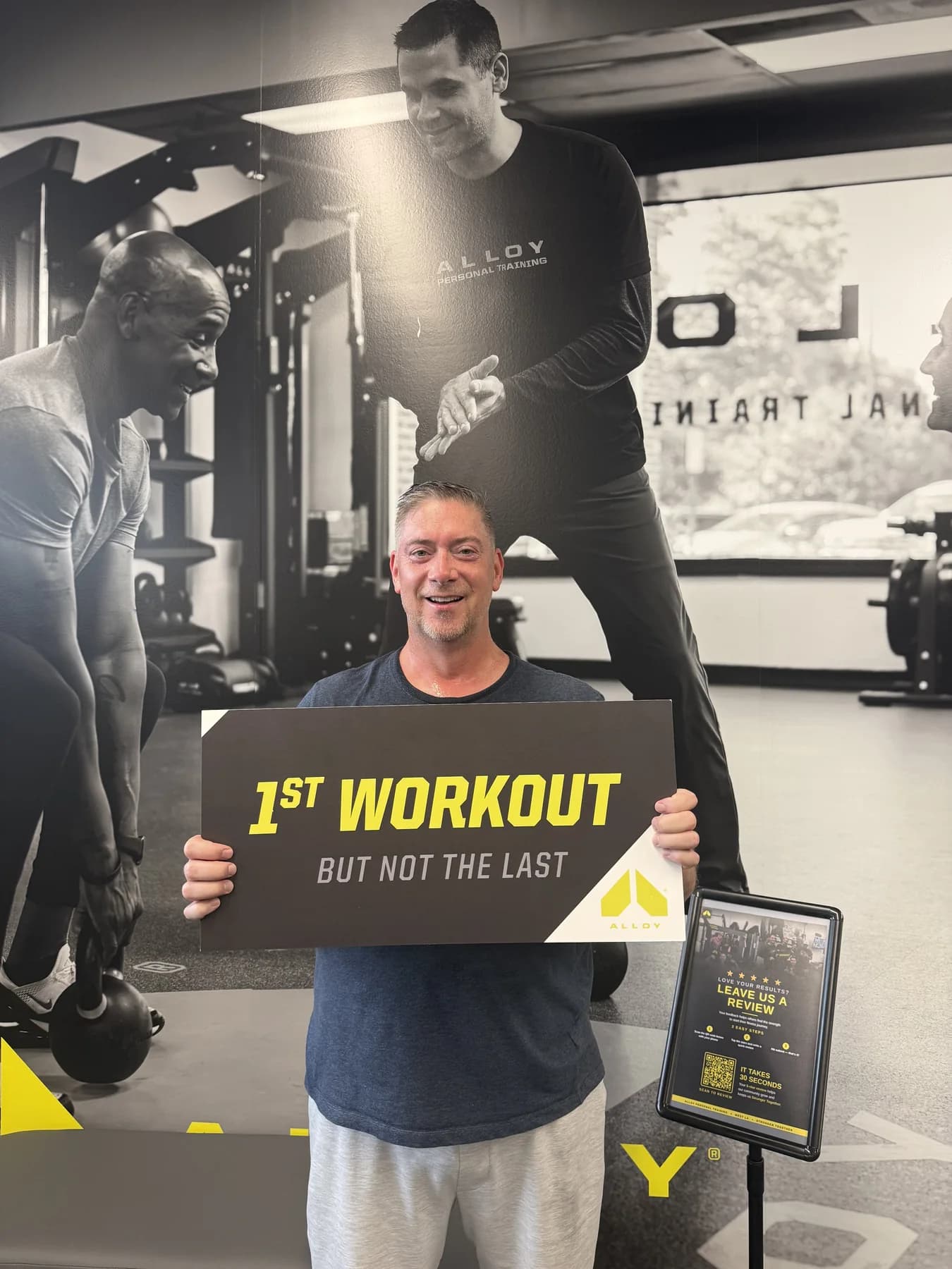 A member celebrating his first workout in front of the Alloy mural