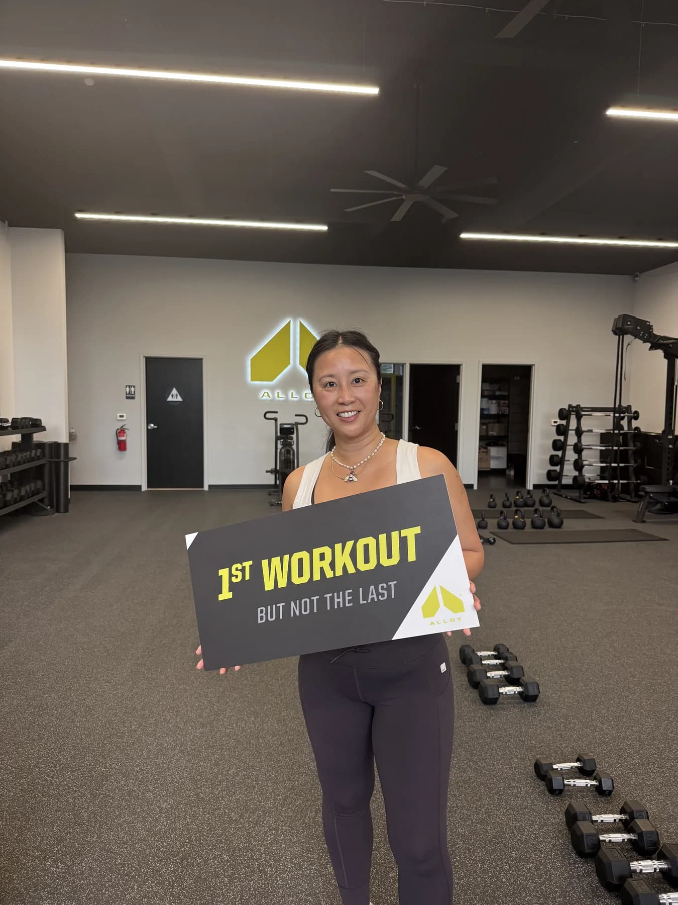 A member smiling with the Alloy first-workout sign