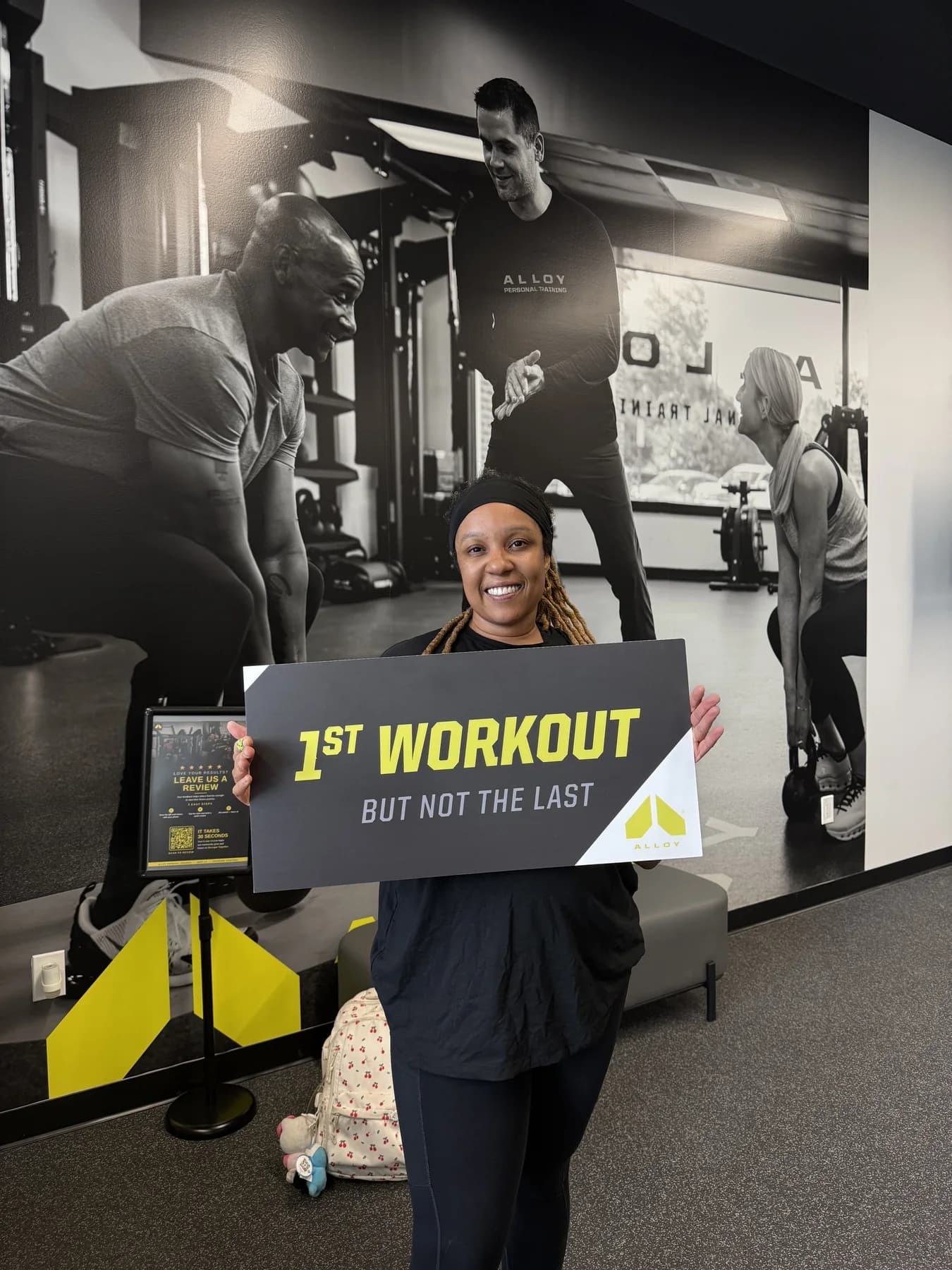 A member holding the first-workout sign after her session
