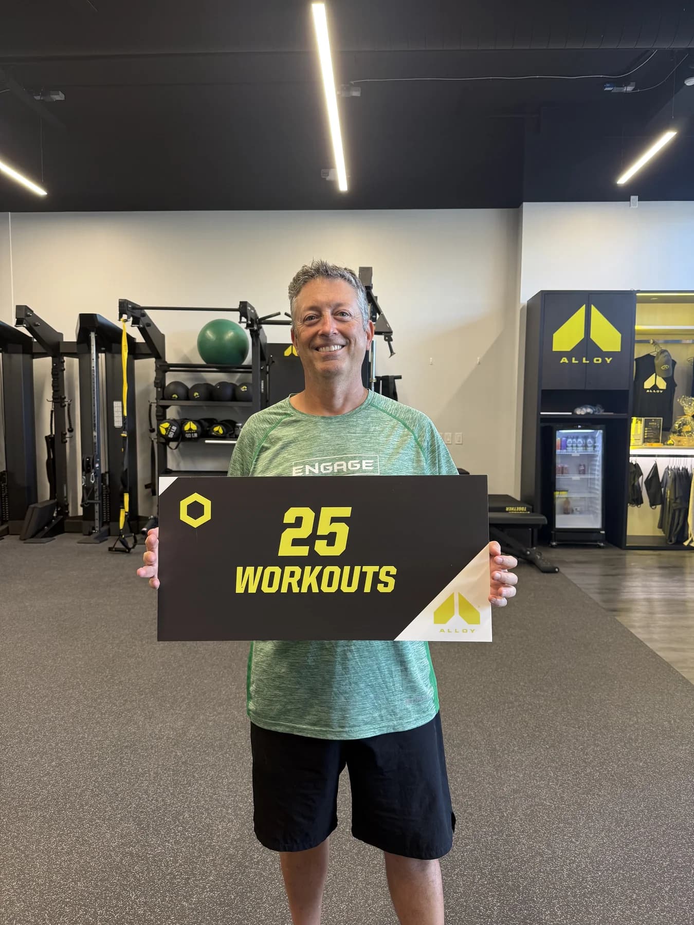 A member holding his twenty-five-workout milestone sign