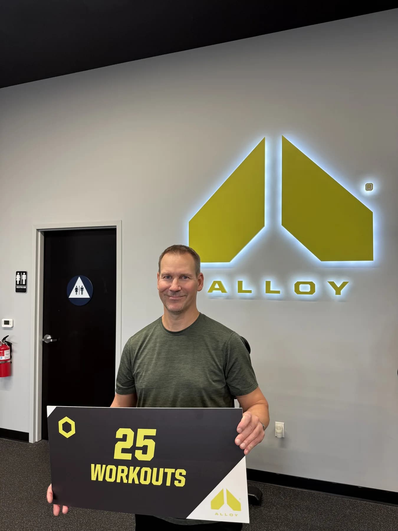 A member smiling with his twenty-five-workout sign