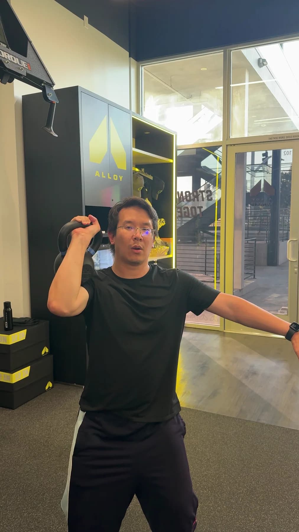 A member performing a standing single-arm kettlebell press