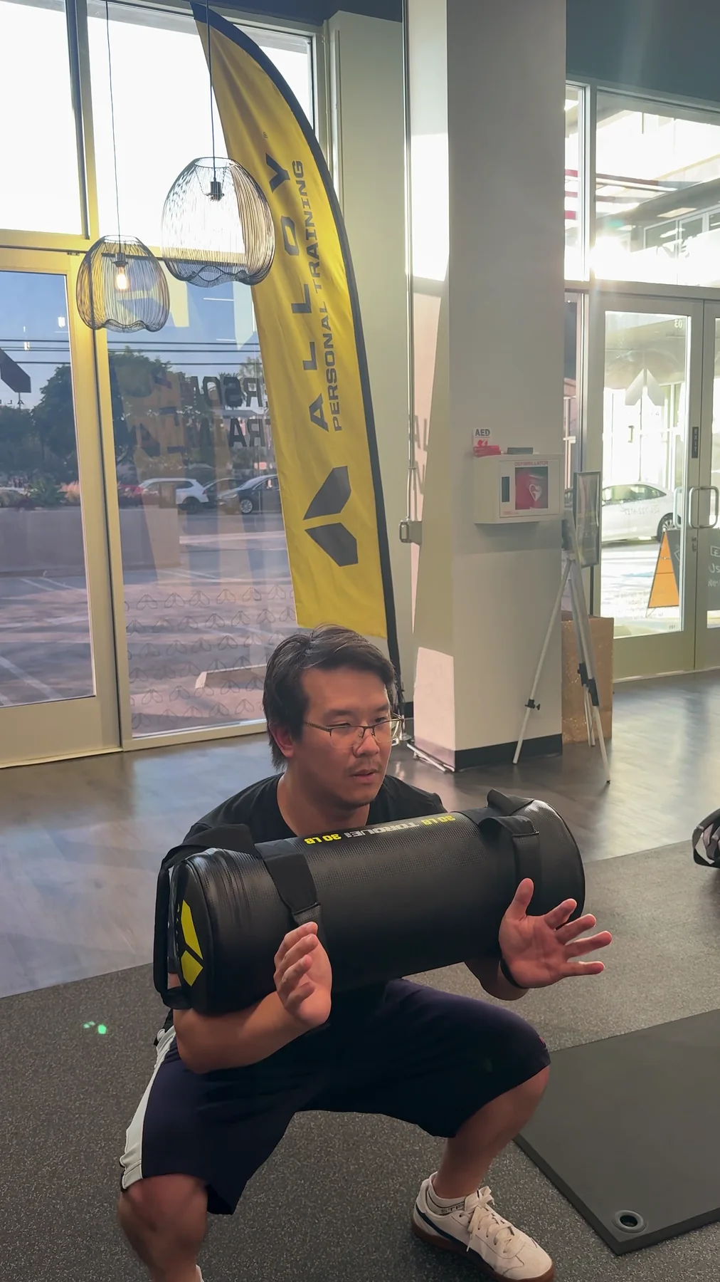 A member holding a sandbag at the bottom of a squat
